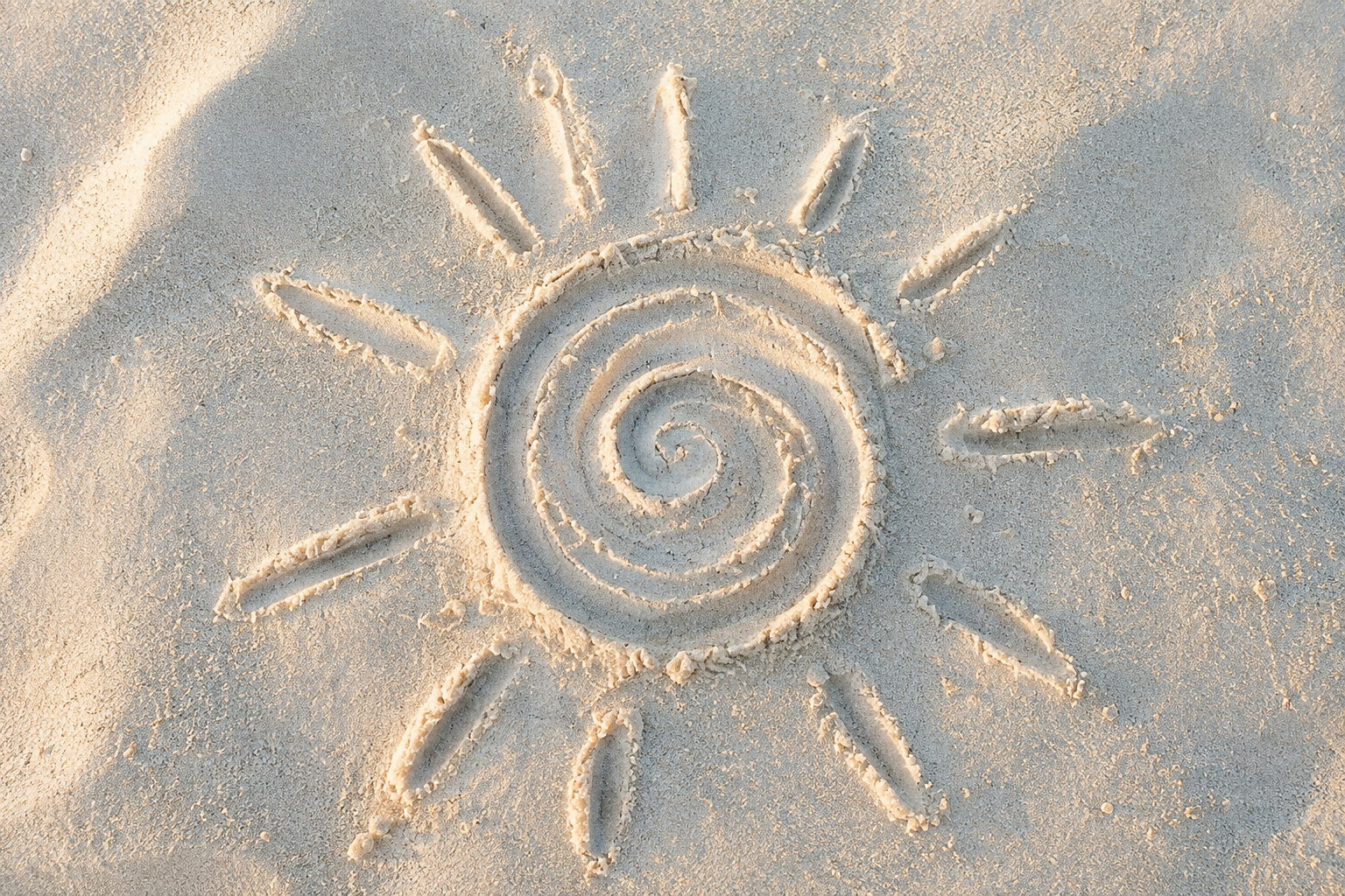 Sunce sa spiralnim središtem nacrtano u svetlom pesku