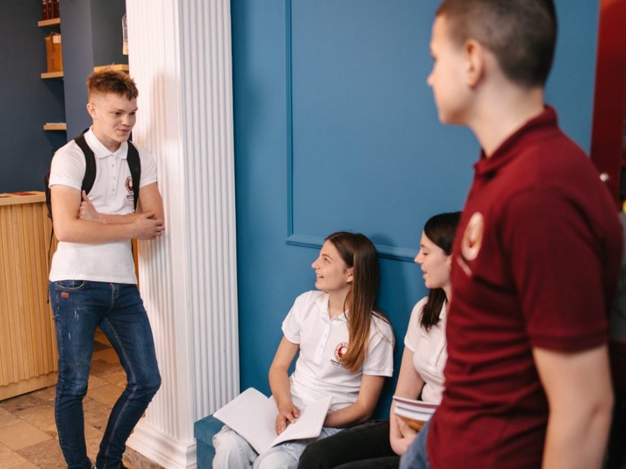Students in school polo shirts talking in a corridor