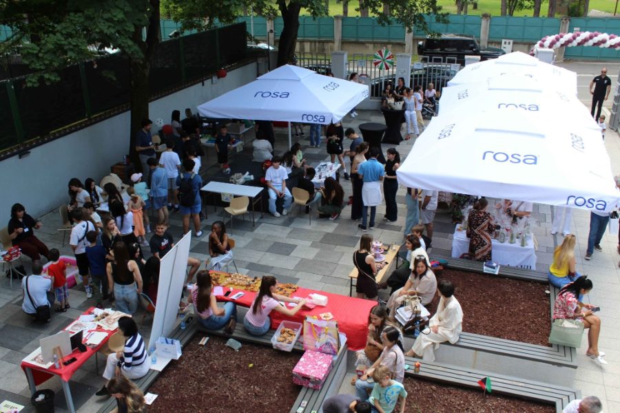 The school courtyard during the Charity Bazaar, with stalls, parasols and students at long tables