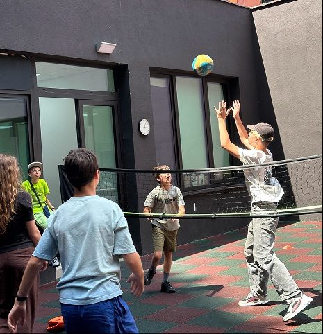 Students playing volleyball over a low net in the school courtyard