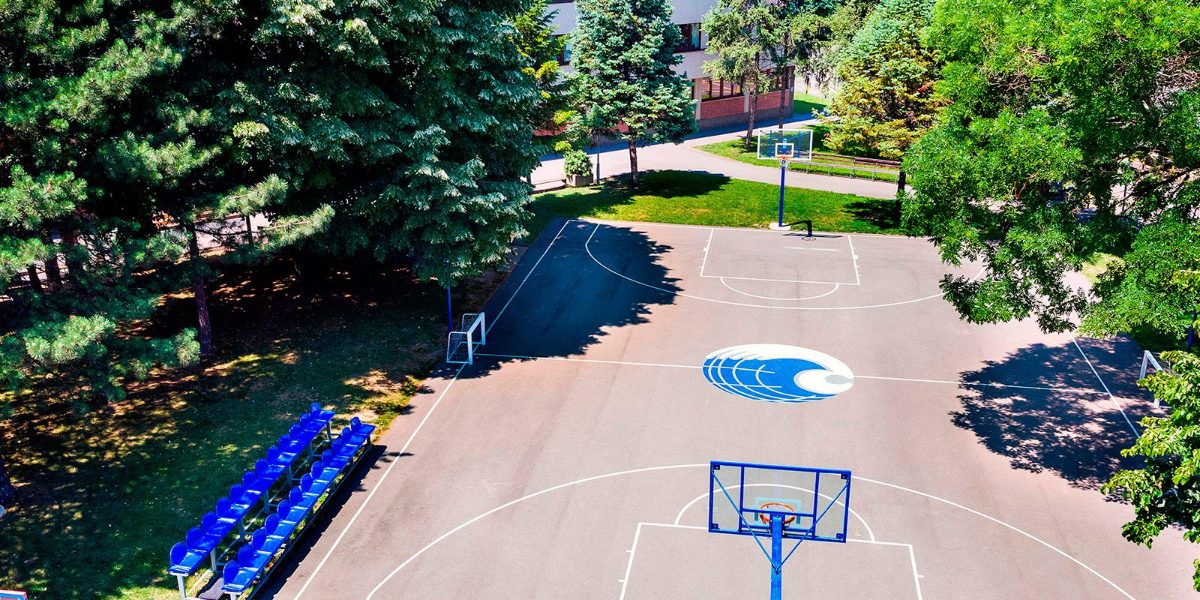 An aerial view of the school basketball court among tall trees