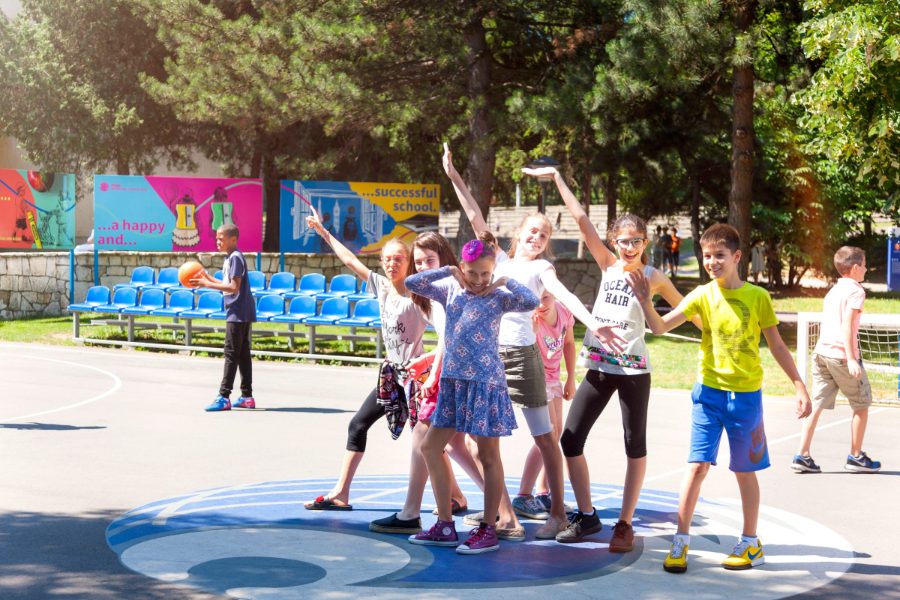 Pupils posing and laughing on the school basketball court on a sunny day